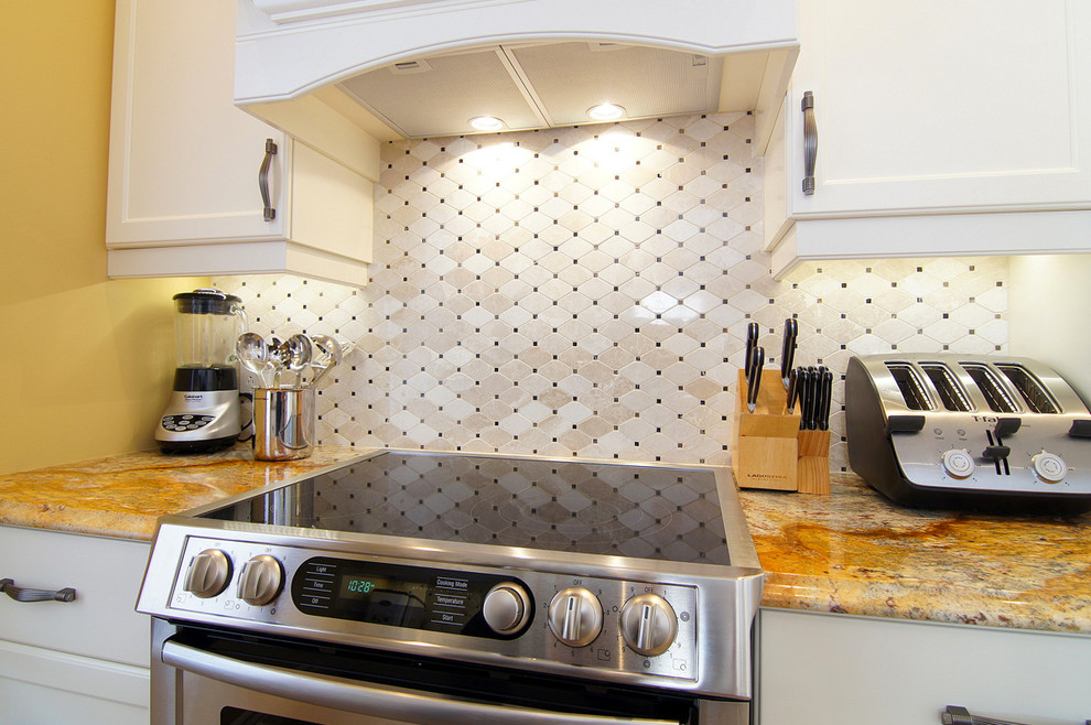 Photo of a mid-sized traditional u-shaped eat-in kitchen in Montreal with shaker cabinets, white cabinets, wood benchtops, beige splashback, mosaic tile splashback, stainless steel appliances, a peninsula and beige floor.
