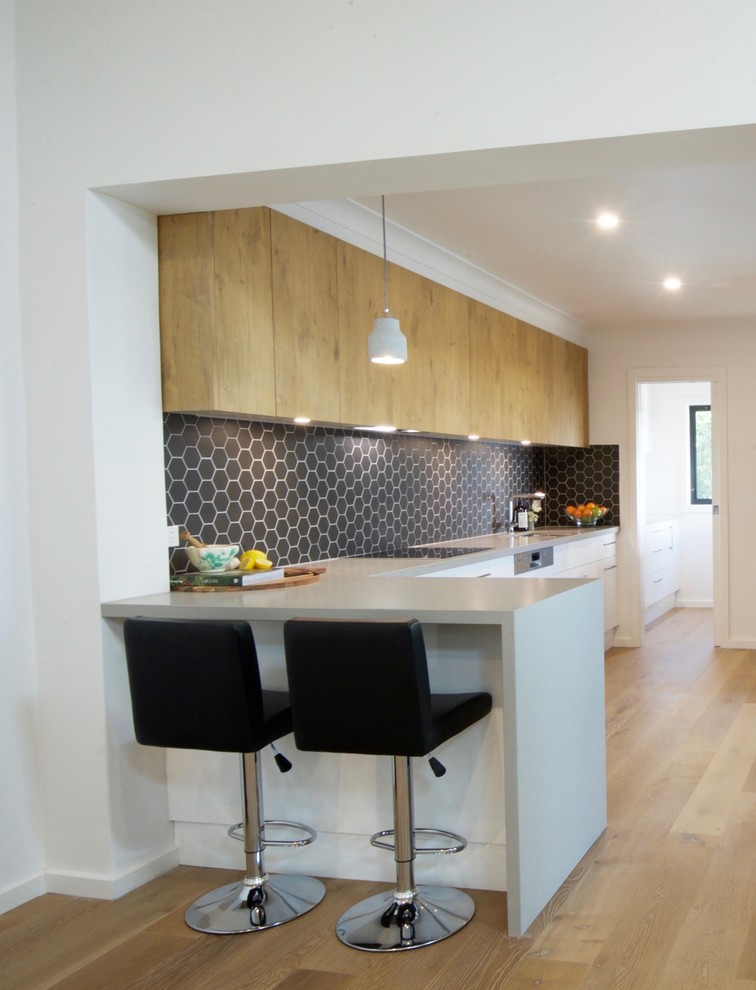 Photo of a mid-sized modern galley eat-in kitchen in Melbourne with an undermount sink, flat-panel cabinets, white cabinets, quartz benchtops, grey splashback, mosaic tile splashback, panelled appliances, light hardwood floors and no island.