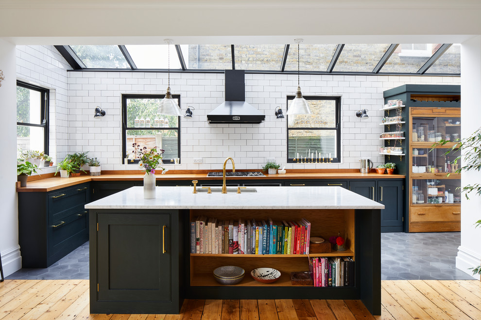 Design ideas for a transitional l-shaped kitchen in London with an undermount sink, shaker cabinets, black cabinets, zinc benchtops, white splashback, subway tile splashback, with island, grey floor and brown benchtop.