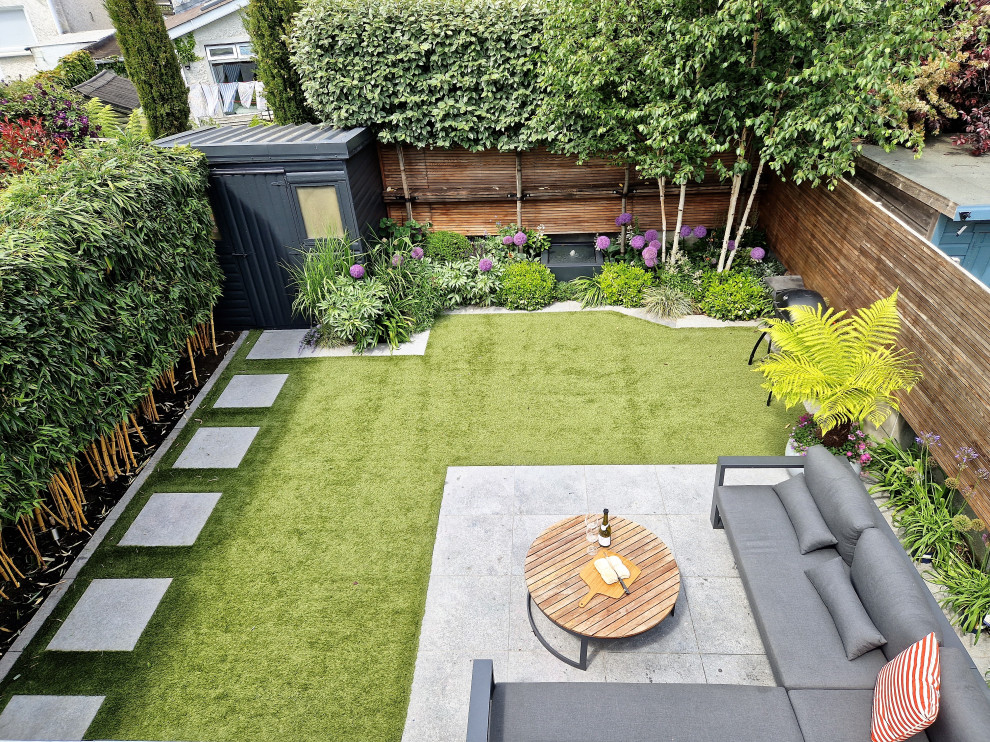 Design ideas for a small contemporary garden in Dublin with natural stone paving and a wood fence.