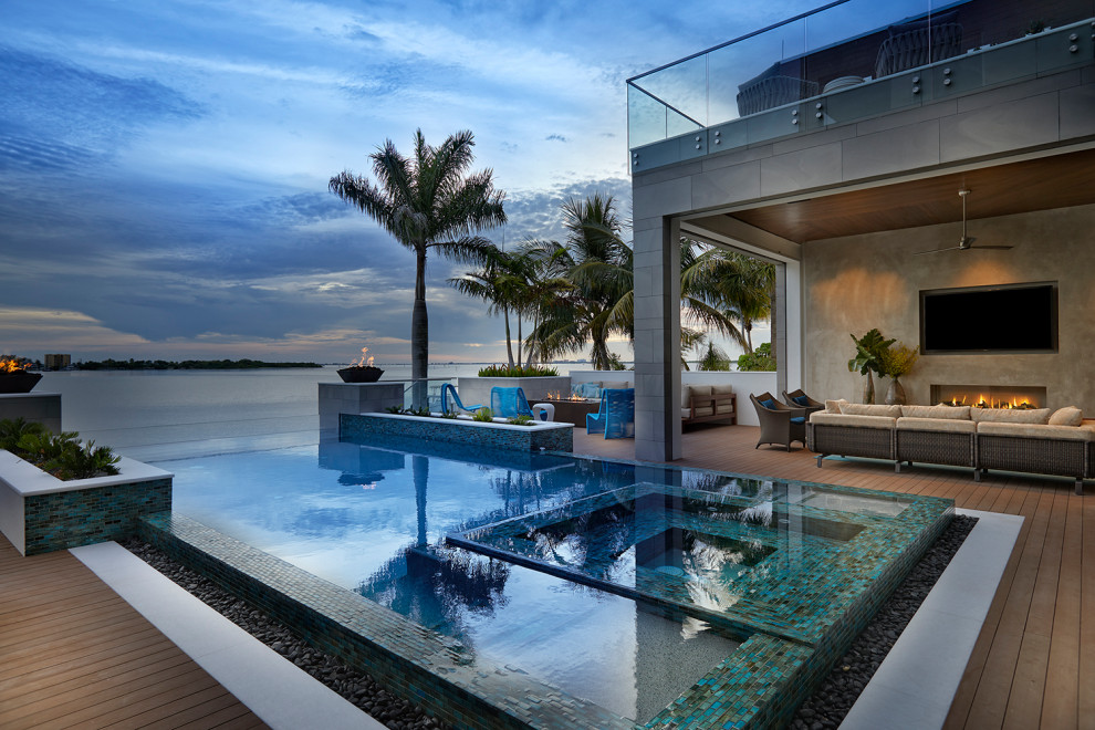 This is an example of a beach style rectangular infinity pool in Miami with a hot tub and decking.