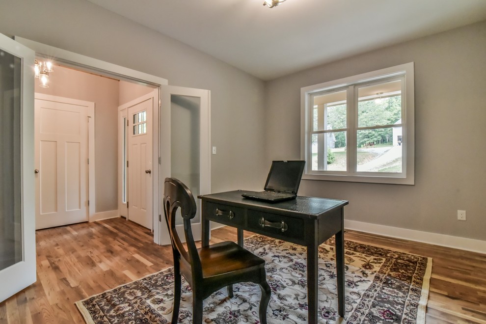This is an example of a large arts and crafts study room in Other with grey walls, brown floor, medium hardwood floors, no fireplace and a freestanding desk.