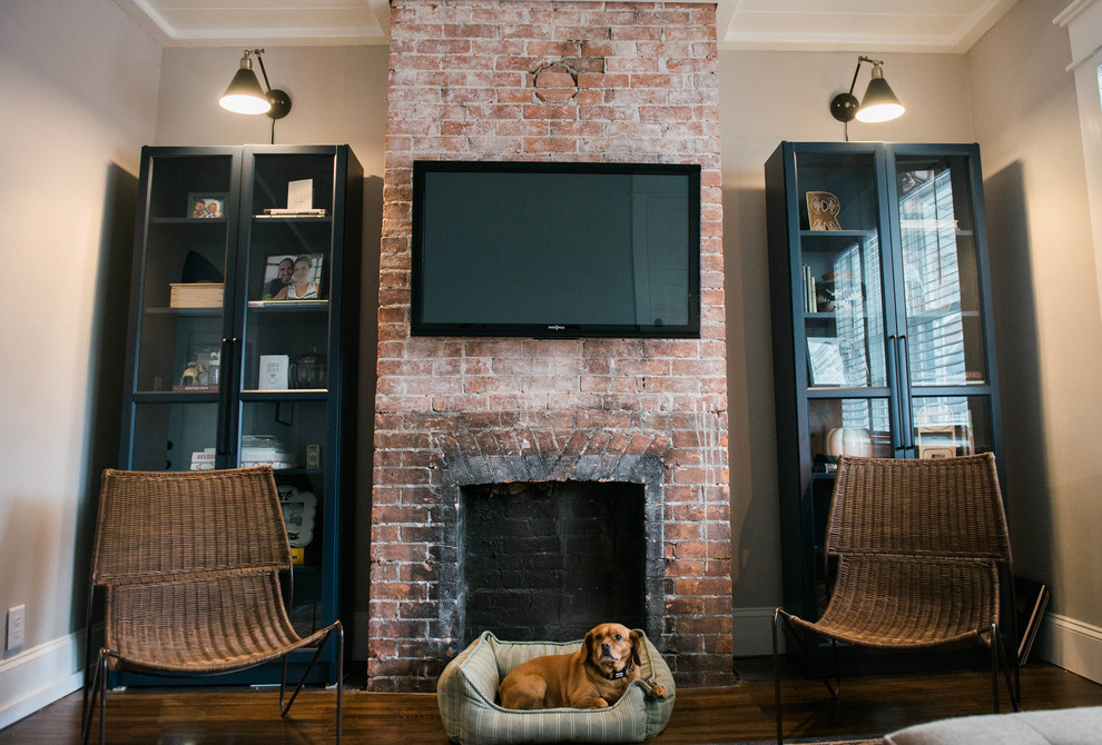 Inspiration for a small eclectic living room in New York with grey walls, dark hardwood floors, a standard fireplace, a brick fireplace surround and a wall-mounted tv.