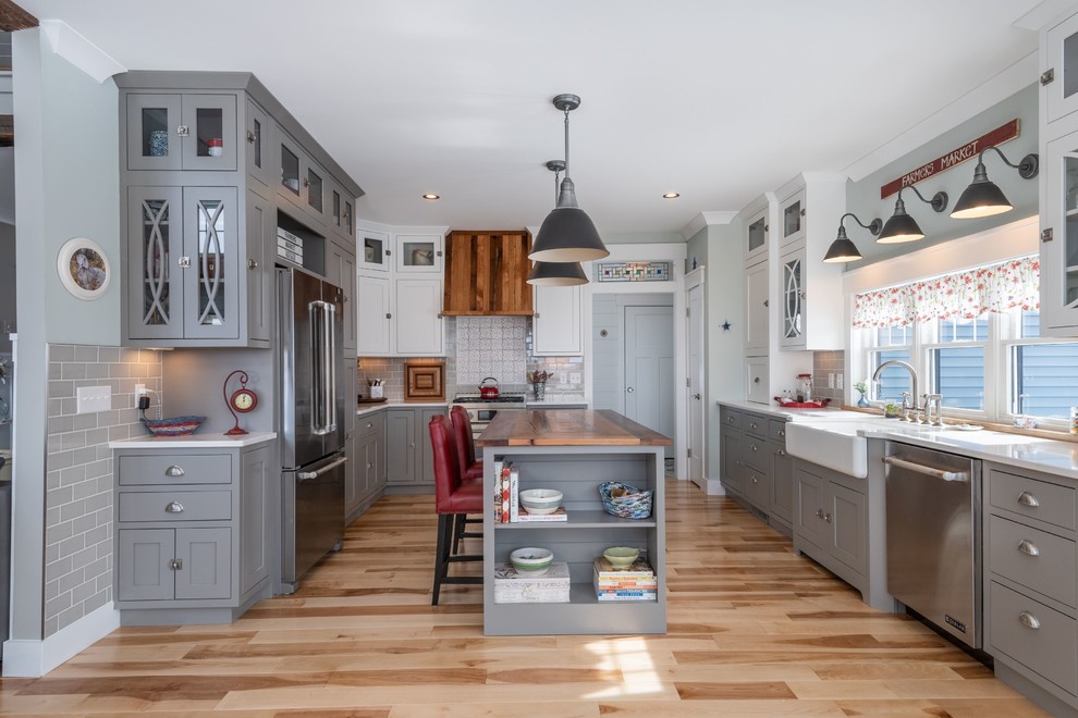 Cottage light wood floor enclosed kitchen photo in Portland Maine with a farmhouse sink, gray cabinets, gray backsplash, stainless steel appliances, an island and white countertops