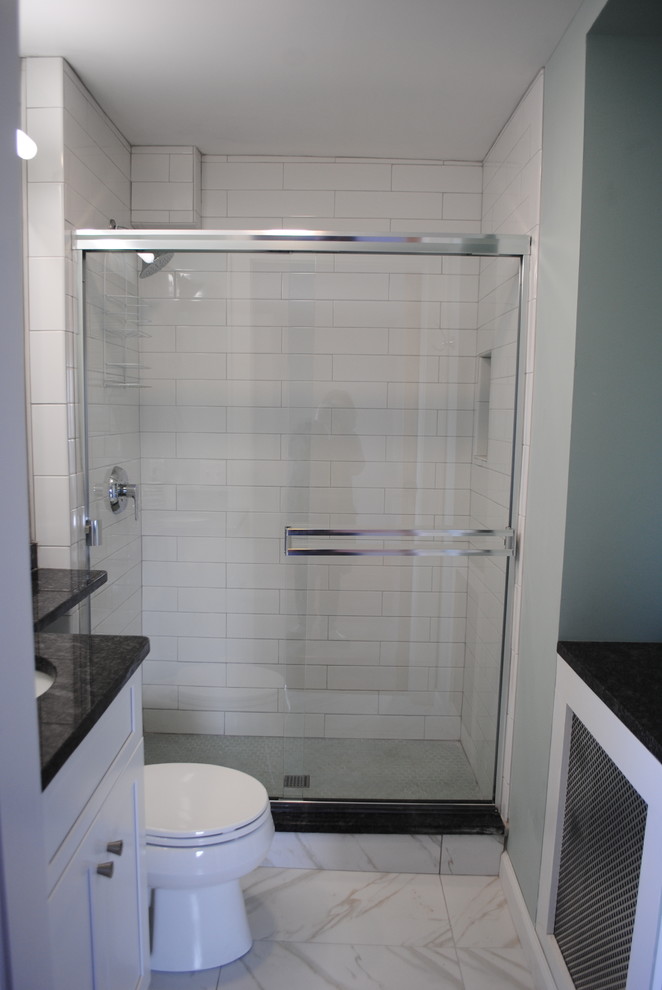 Photo of a small transitional 3/4 bathroom in Boston with shaker cabinets, white cabinets, an alcove shower, a two-piece toilet, blue tile, subway tile, porcelain floors, an undermount sink, white floor, a sliding shower screen, grey walls, granite benchtops and black benchtops.