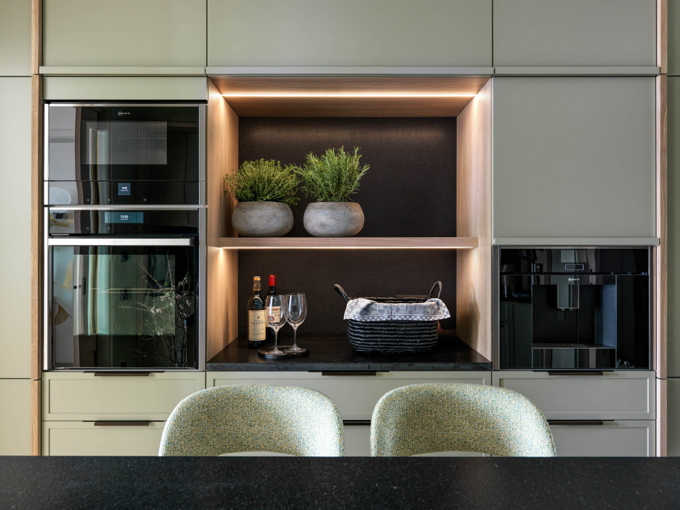 Mid-sized contemporary galley separate kitchen in Moscow with an undermount sink, flat-panel cabinets, green cabinets, granite benchtops, black splashback, stone slab splashback, black appliances, terrazzo floors, with island, white floor and black benchtop.