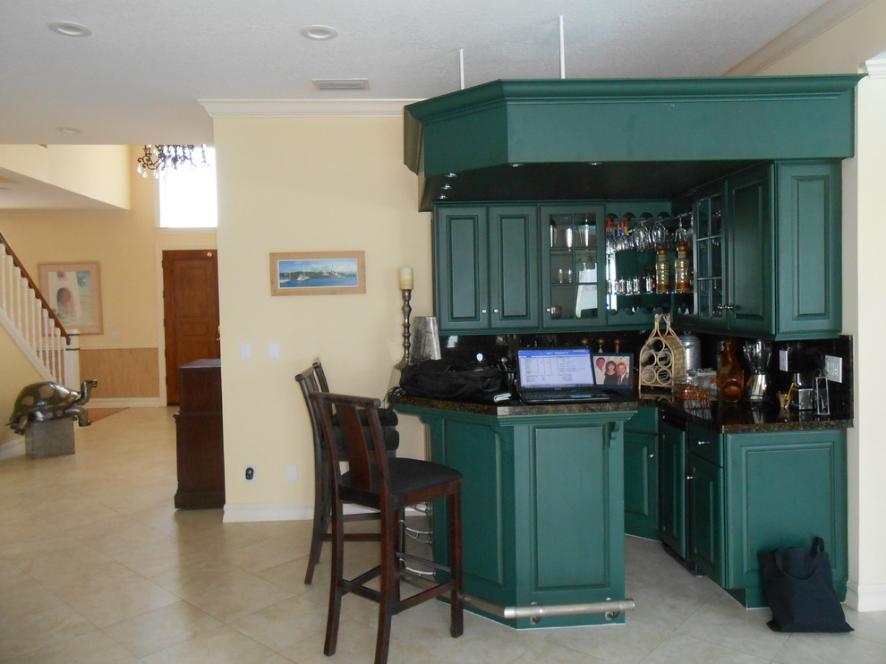 Large eclectic single-wall seated home bar in Tampa with a drop-in sink, raised-panel cabinets, green cabinets, granite benchtops, multi-coloured splashback and travertine floors.