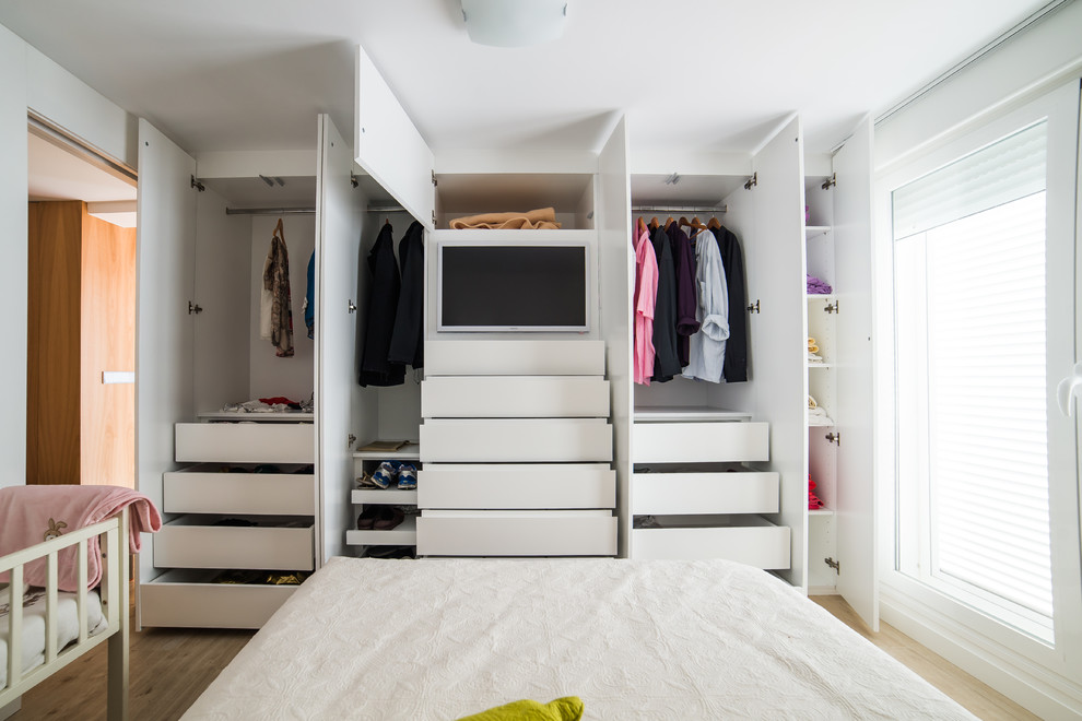 Mid-sized contemporary gender-neutral built-in wardrobe in Other with flat-panel cabinets, white cabinets and medium hardwood floors.