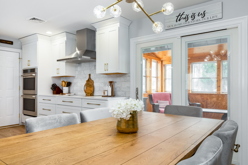 Foto på ett mellanstort vintage vit kök, med en undermonterad diskho, skåp i shakerstil, vita skåp, bänkskiva i kvarts, grått stänkskydd, stänkskydd i marmor, rostfria vitvaror, ljust trägolv, en halv köksö och brunt golv