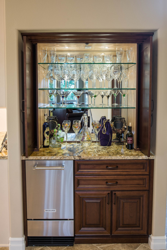 Photo of a large traditional u-shaped home bar in Seattle with raised-panel cabinets, white cabinets, granite benchtops, beige splashback, limestone splashback, porcelain floors, multi-coloured floor and brown benchtop.