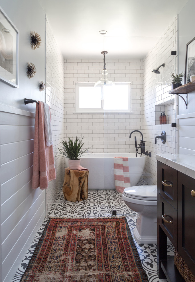 This is an example of a mid-sized country 3/4 bathroom in Los Angeles with shaker cabinets, brown cabinets, a freestanding tub, a curbless shower, a two-piece toilet, white tile, subway tile, grey walls, cement tiles, an undermount sink, marble benchtops, black floor and an open shower.