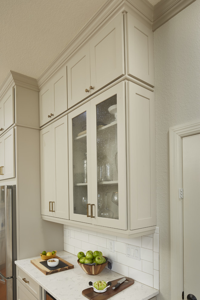 Mid-sized transitional u-shaped medium tone wood floor and brown floor enclosed kitchen photo in Atlanta with a farmhouse sink, shaker cabinets, gray cabinets, quartz countertops, white backsplash, subway tile backsplash, stainless steel appliances, a peninsula and white countertops