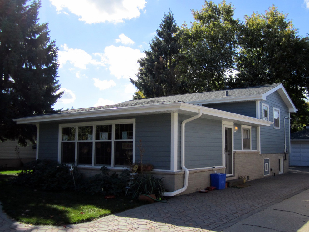 Photo of a mid-sized traditional split-level blue house exterior in Other with concrete fiberboard siding, a flat roof and a shingle roof.