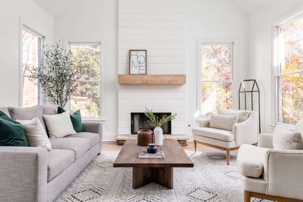 Inspiration for a medium sized classic open plan living room in Atlanta with white walls, light hardwood flooring, a standard fireplace, a timber clad chimney breast, multi-coloured floors and a vaulted ceiling.