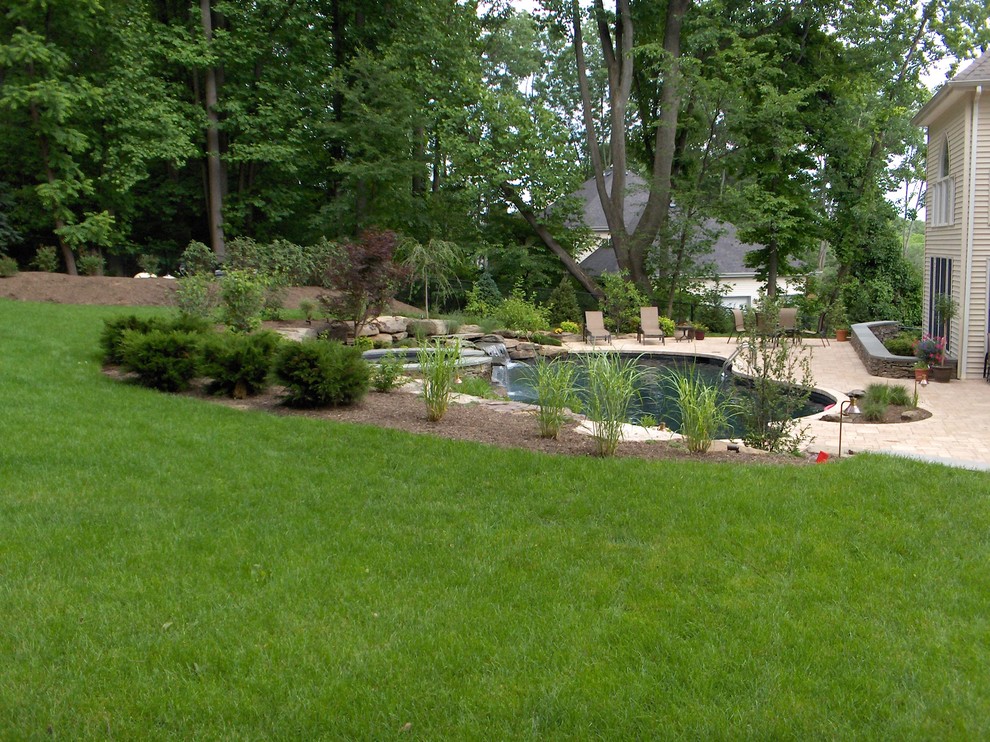 Design ideas for a large country front yard custom-shaped natural pool in New York with concrete pavers and a hot tub.