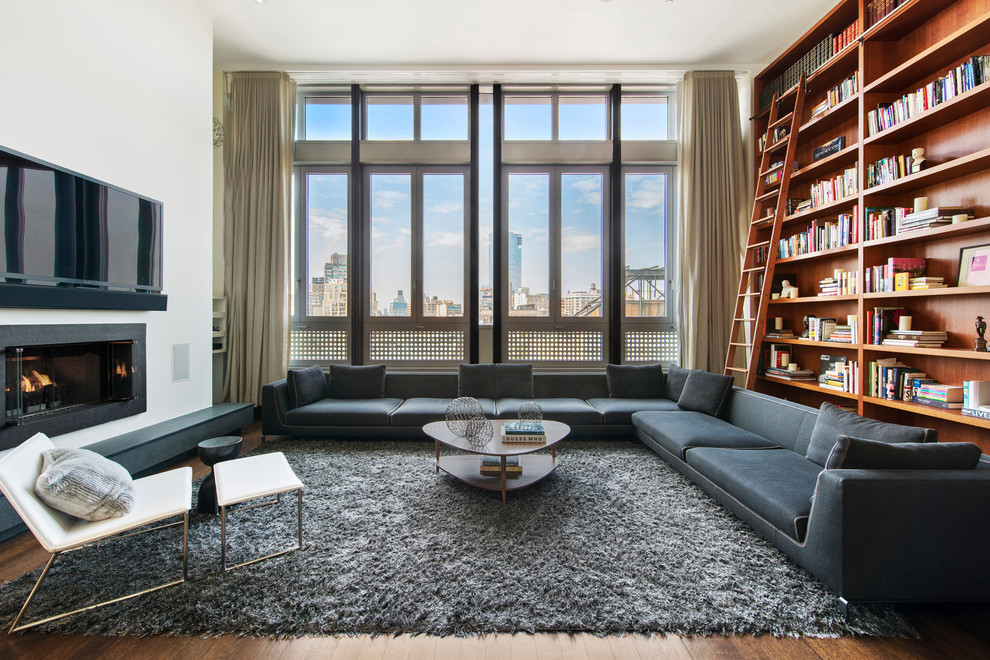 Photo of a contemporary living room in New York with a library, white walls, medium hardwood floors, a ribbon fireplace, a metal fireplace surround and a wall-mounted tv.