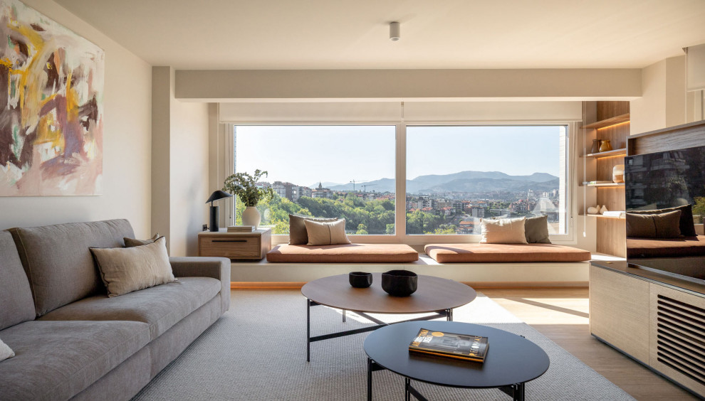 Exempel på ett modernt vardagsrum, med beige väggar, ljust trägolv, en fristående TV och beiget golv