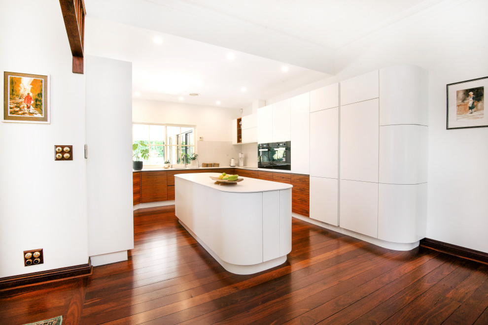 Immagine di una cucina minimal con ante bianche, paraspruzzi in gres porcellanato, parquet scuro, pavimento marrone e top bianco