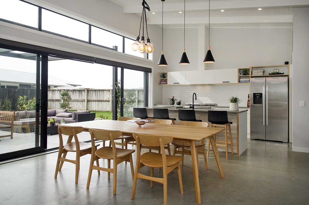 Inspiration for a contemporary galley eat-in kitchen in Dunedin with flat-panel cabinets, white cabinets, white splashback, stainless steel appliances, concrete floors, with island, grey floor and grey benchtop.