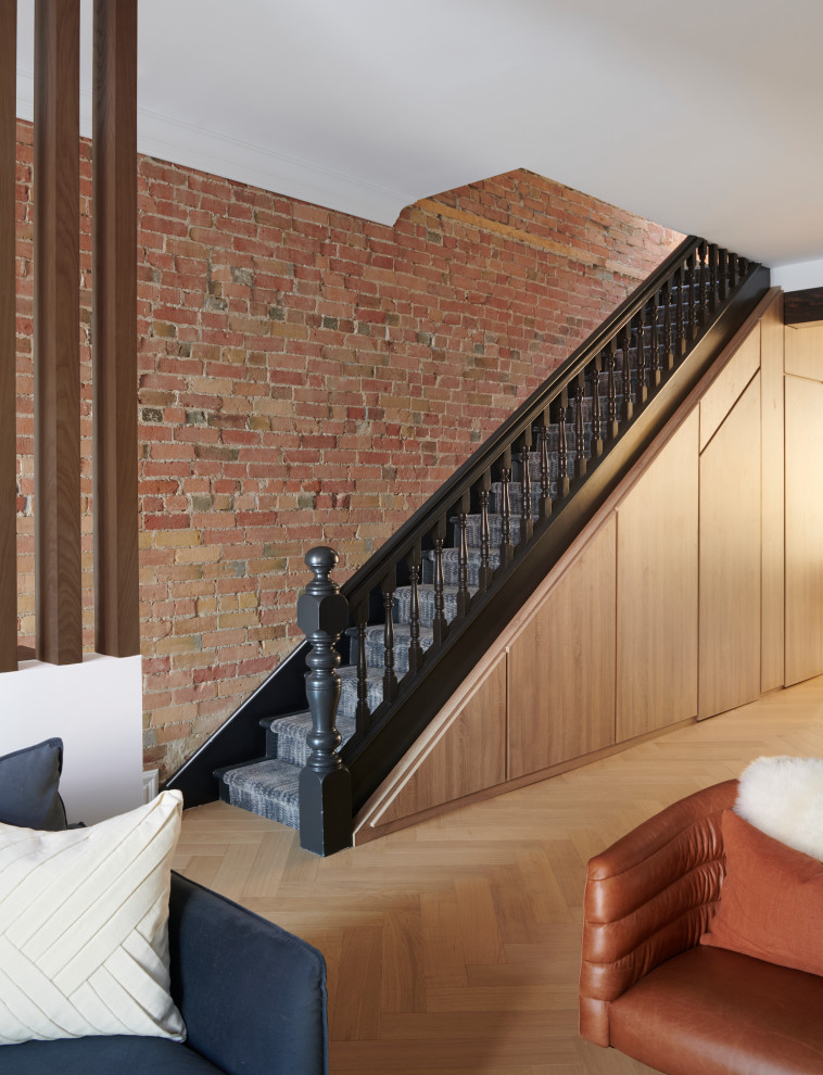 Photo of a small contemporary carpeted straight staircase in Toronto with carpet risers, wood railing and brick walls.