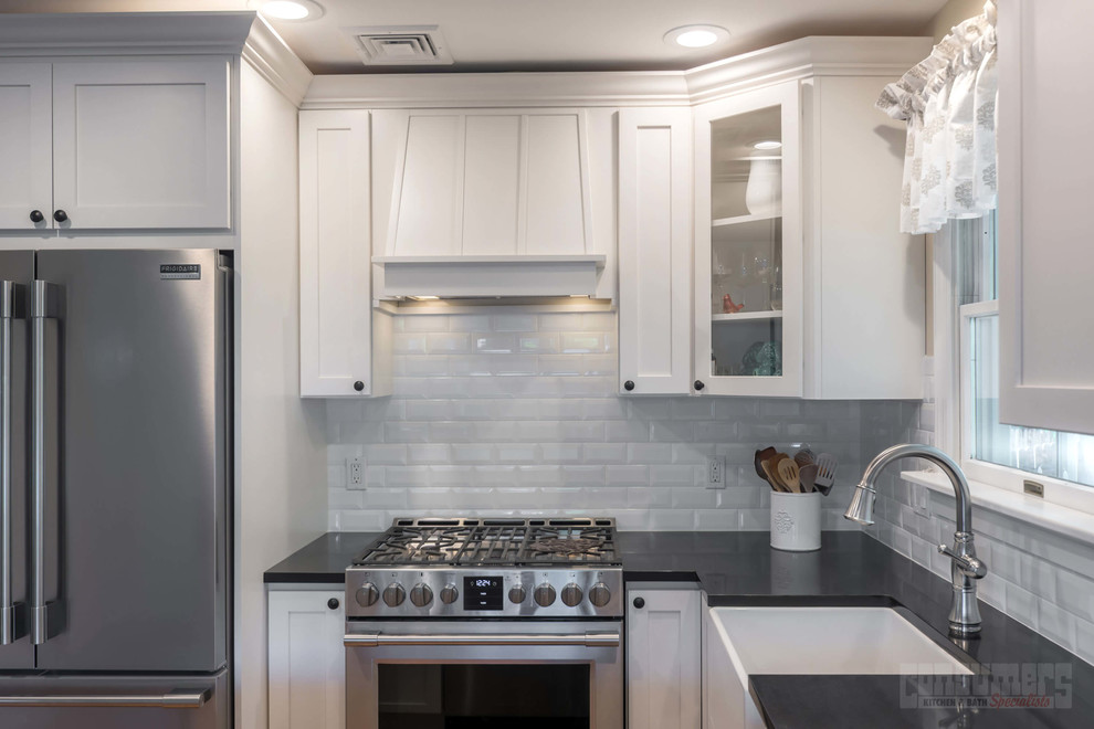 Small transitional l-shaped eat-in kitchen in New York with a farmhouse sink, shaker cabinets, white cabinets, quartz benchtops, yellow splashback, stainless steel appliances and a peninsula.