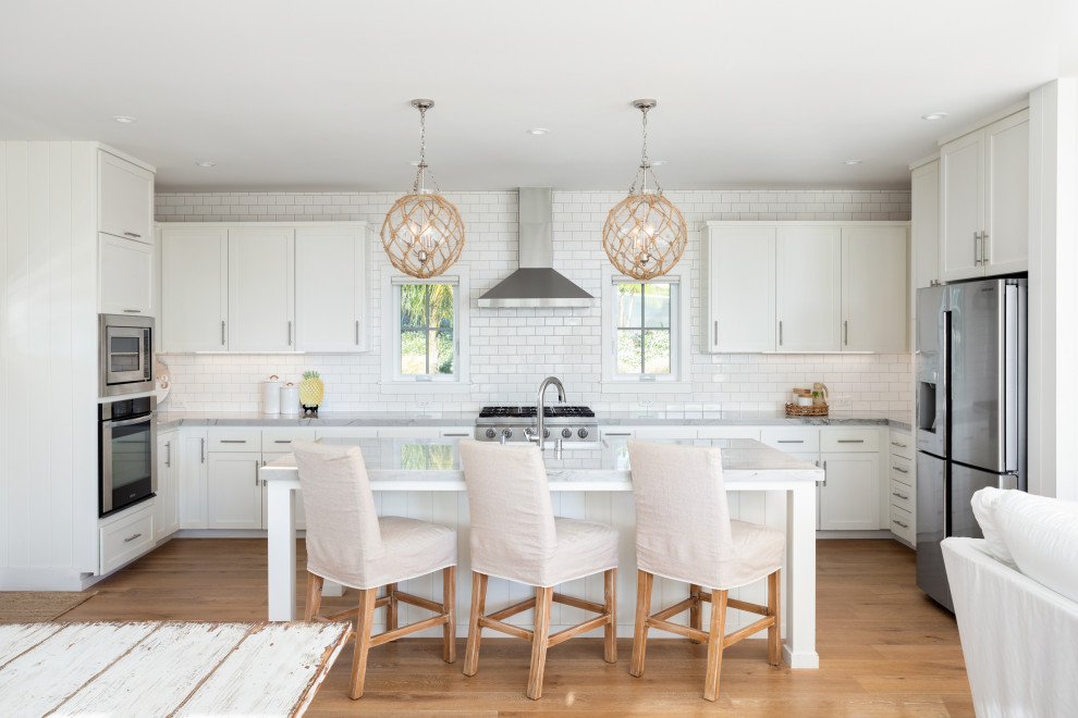 Inspiration for a large transitional u-shaped eat-in kitchen in San Diego with a farmhouse sink, shaker cabinets, white cabinets, marble benchtops, white splashback, subway tile splashback, stainless steel appliances, with island, medium hardwood floors, beige floor and grey benchtop.