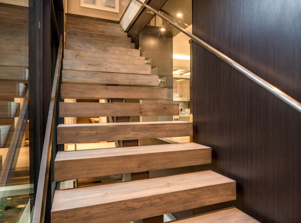 На фото: большая лестница на больцах в стиле модернизм с деревянными ступенями, металлическими перилами и деревянными стенами с