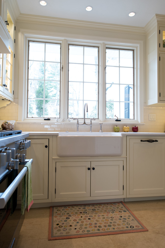 Photo of a mid-sized traditional u-shaped eat-in kitchen in Philadelphia with a farmhouse sink, beaded inset cabinets, white cabinets, quartz benchtops, white splashback, subway tile splashback, panelled appliances, limestone floors, with island, beige floor and white benchtop.