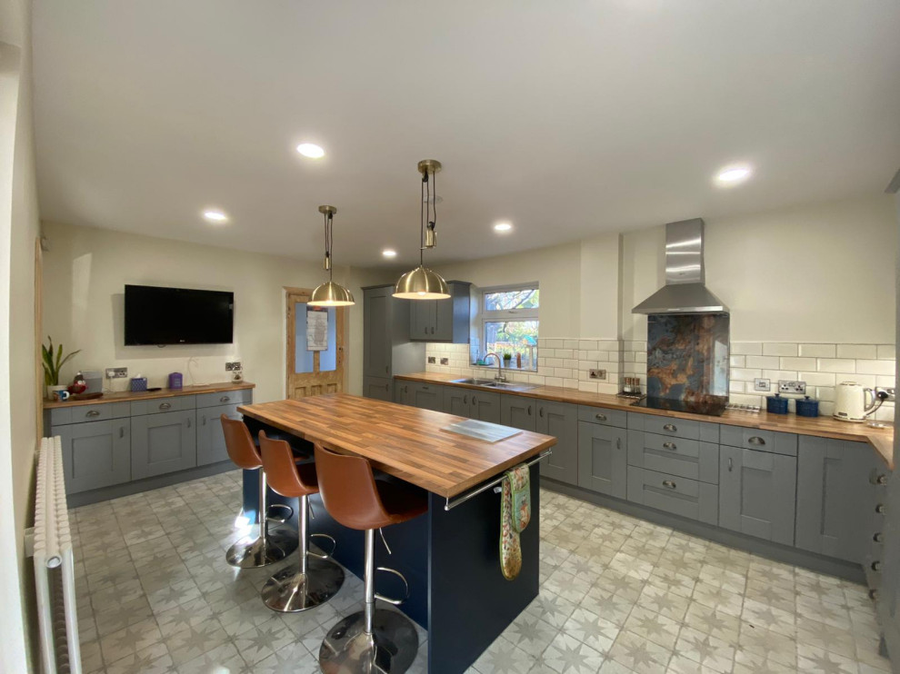 Large classic l-shaped kitchen in Other with shaker cabinets, laminate countertops and an island.