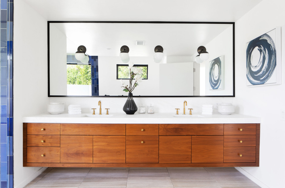 Inspiration for a mid-sized contemporary master wet room bathroom in Los Angeles with flat-panel cabinets, medium wood cabinets, a freestanding tub, a one-piece toilet, white tile, ceramic tile, white walls, an undermount sink, solid surface benchtops, grey floor, an open shower and white benchtops.