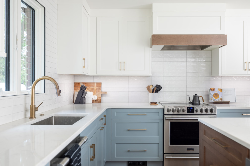 Transitional l-shaped kitchen photo with an undermount sink, shaker cabinets, blue cabinets, white backsplash, stainless steel appliances, an island and white countertops
