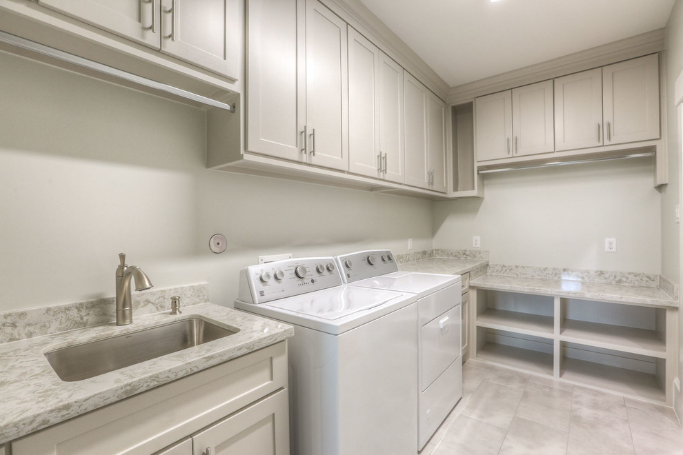 Example of a large transitional l-shaped ceramic tile and beige floor dedicated laundry room design in Houston with an undermount sink, shaker cabinets, beige cabinets, granite countertops, white walls and a side-by-side washer/dryer