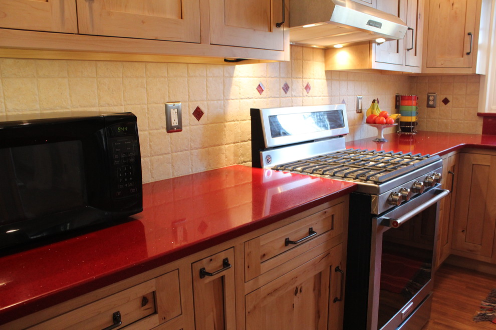 Example of a mid-sized mountain style l-shaped laminate floor enclosed kitchen design in Philadelphia with a double-bowl sink, shaker cabinets, light wood cabinets, quartz countertops, beige backsplash, ceramic backsplash, stainless steel appliances and no island