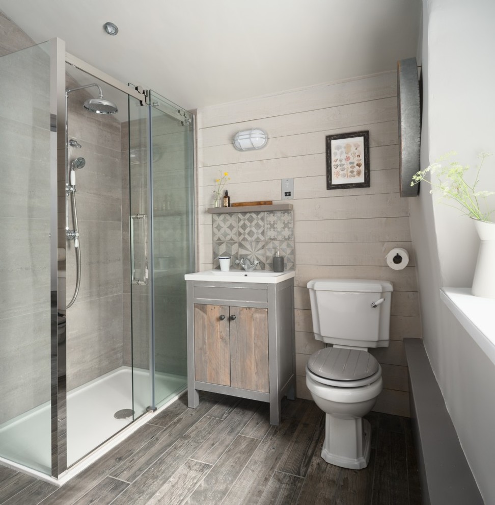 Design ideas for a small beach style bathroom in Glasgow with flat-panel cabinets, light wood cabinets, a corner shower, a two-piece toilet, a console sink, grey floor, a sliding shower screen, gray tile and beige walls.