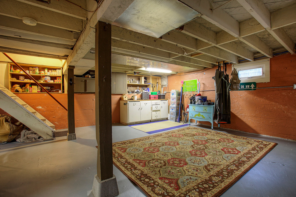 This is an example of a mid-sized traditional walk-out basement in Seattle with orange walls and concrete floors.