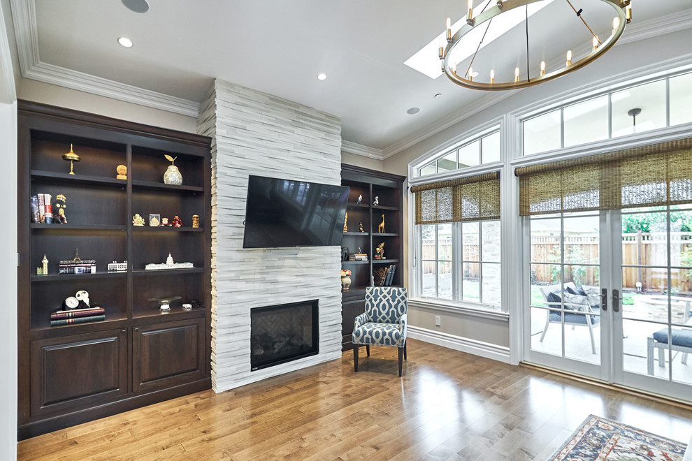This is an example of a large transitional open concept family room in San Francisco with grey walls, medium hardwood floors, a standard fireplace, a stone fireplace surround, a wall-mounted tv and brown floor.