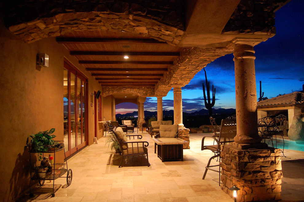 Design ideas for a large mediterranean backyard patio in Phoenix with natural stone pavers and a roof extension.