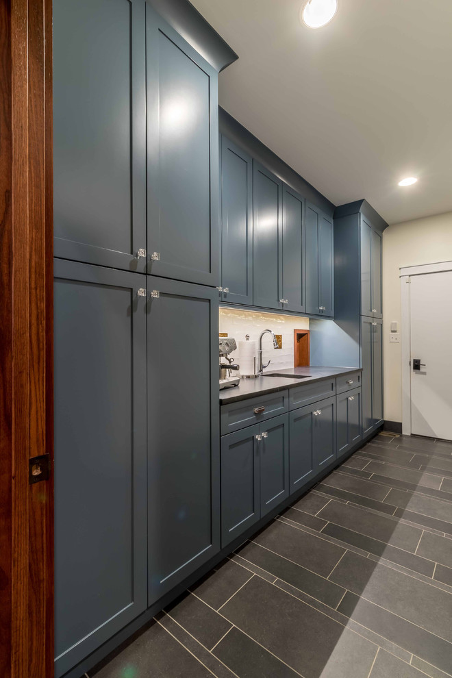 Inspiration for a mid-sized arts and crafts single-wall wet bar in Chicago with an undermount sink, beaded inset cabinets, blue cabinets, granite benchtops, white splashback, cement tile splashback, ceramic floors, brown floor and black benchtop.