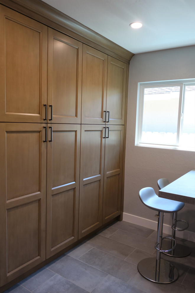 This is an example of a mid-sized transitional u-shaped kitchen pantry in San Francisco with an undermount sink, recessed-panel cabinets, white cabinets, solid surface benchtops, grey splashback, marble splashback, porcelain floors, a peninsula, grey floor and grey benchtop.