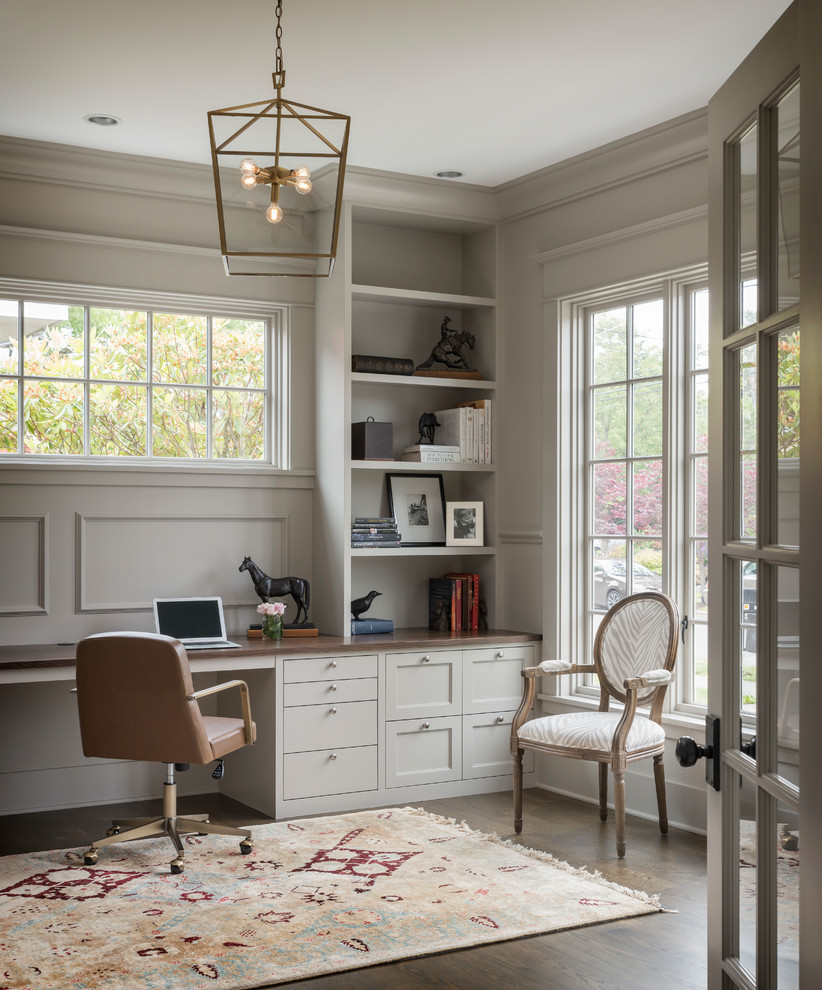 Photo of a transitional home office in Seattle with grey walls, dark hardwood floors, a built-in desk and brown floor.