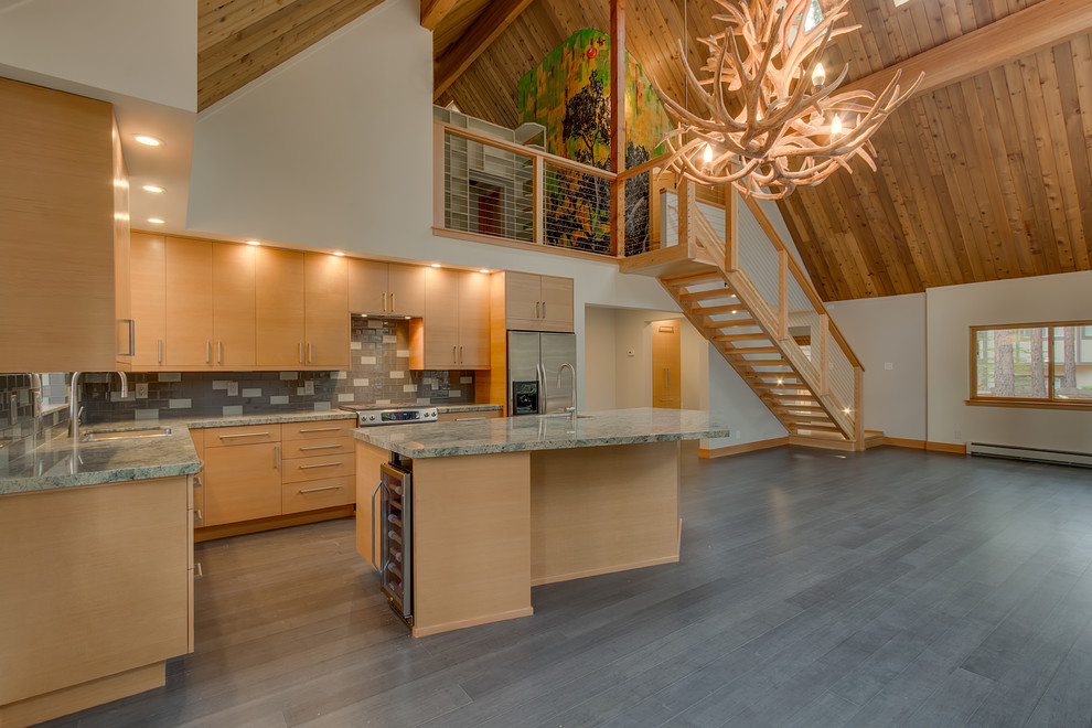 Example of a large trendy l-shaped light wood floor and gray floor open concept kitchen design with a double-bowl sink, flat-panel cabinets, light wood cabinets, granite countertops, gray backsplash, subway tile backsplash, stainless steel appliances and an island