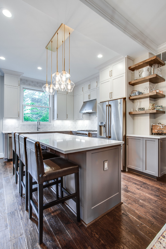 Large transitional l-shaped medium tone wood floor and brown floor eat-in kitchen photo in DC Metro with an island, an undermount sink, shaker cabinets, white cabinets, solid surface countertops, white backsplash, ceramic backsplash, stainless steel appliances and white countertops