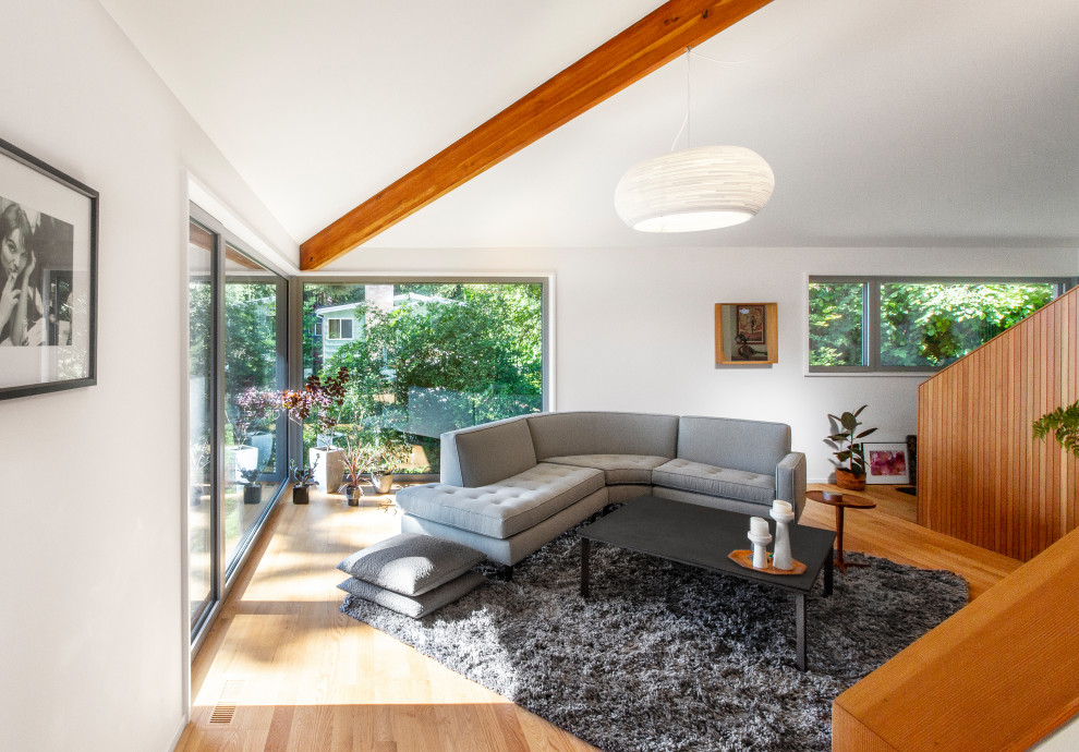 Photo of a mid-sized midcentury loft-style living room in Seattle with white walls, light hardwood floors, a wood stove and no tv.