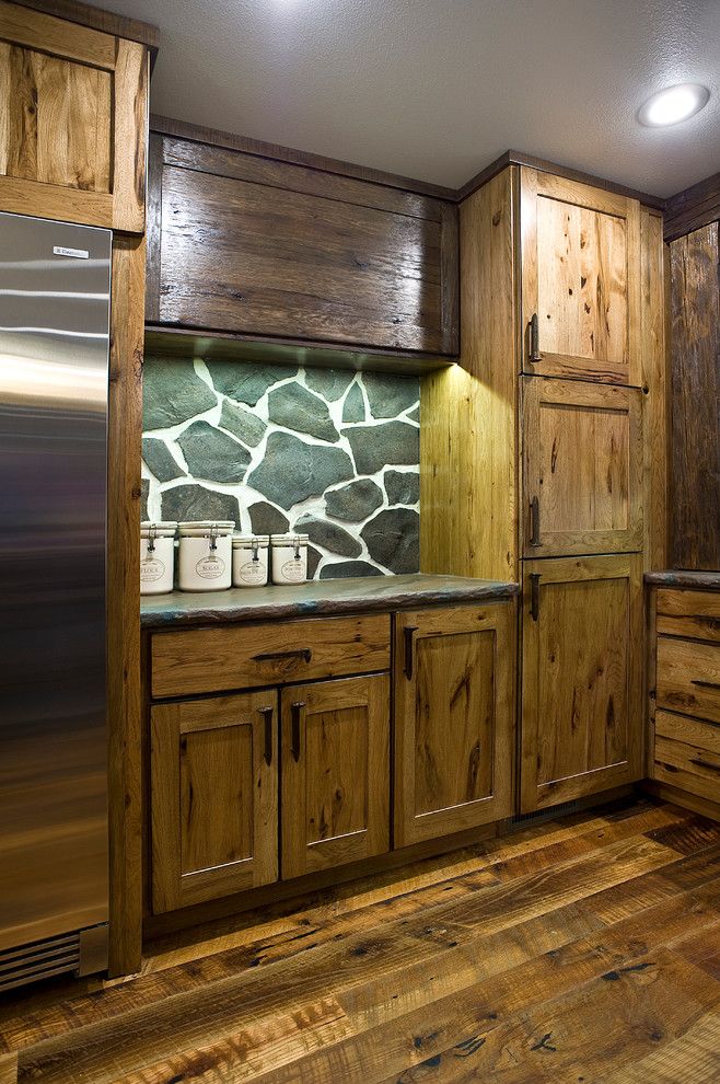 Example of a mid-sized mountain style l-shaped medium tone wood floor eat-in kitchen design with a farmhouse sink, shaker cabinets, distressed cabinets, concrete countertops, gray backsplash, stone slab backsplash, stainless steel appliances and an island