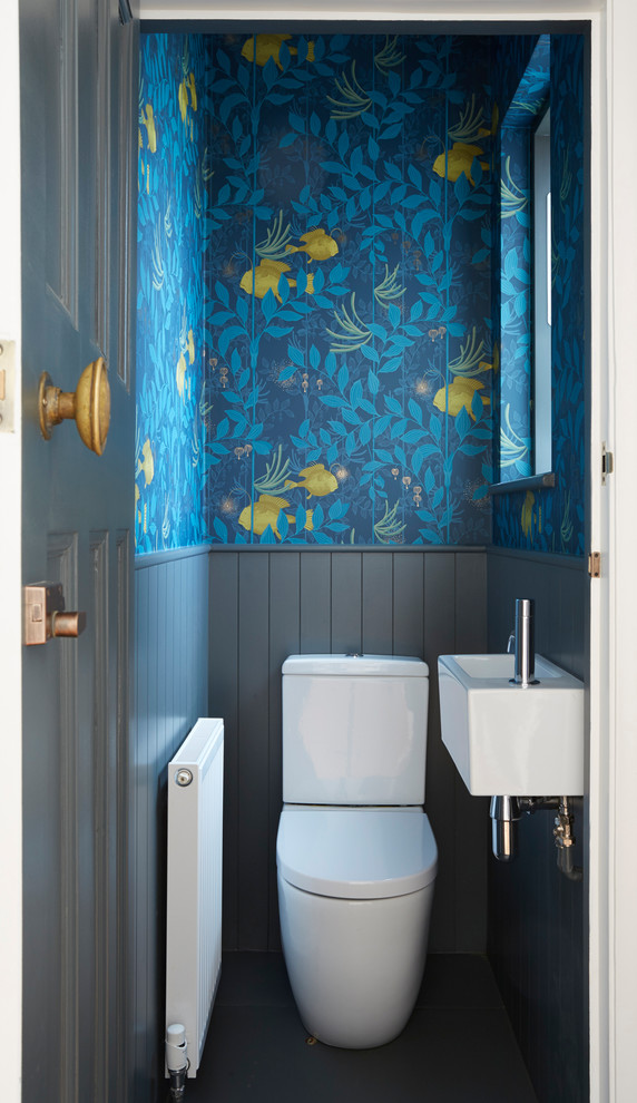 Small transitional powder room in London with a two-piece toilet, blue walls, a wall-mount sink and grey floor.