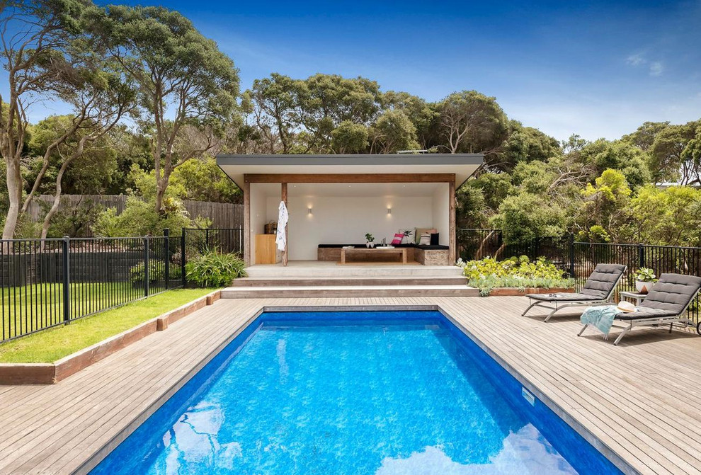 This is an example of a beach style backyard rectangular lap pool in Melbourne with a pool house and decking.