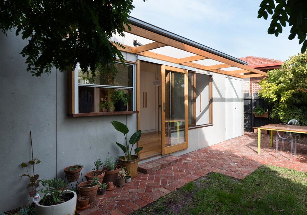 Small scandinavian one-storey concrete grey house exterior in Melbourne with a hip roof and a metal roof.
