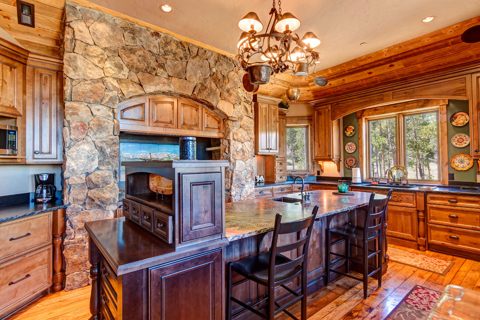 Inspiration for a large rustic u-shaped medium tone wood floor and brown floor eat-in kitchen remodel with louvered cabinets, distressed cabinets, granite countertops, beige backsplash, stone tile backsplash, stainless steel appliances, an island and red countertops