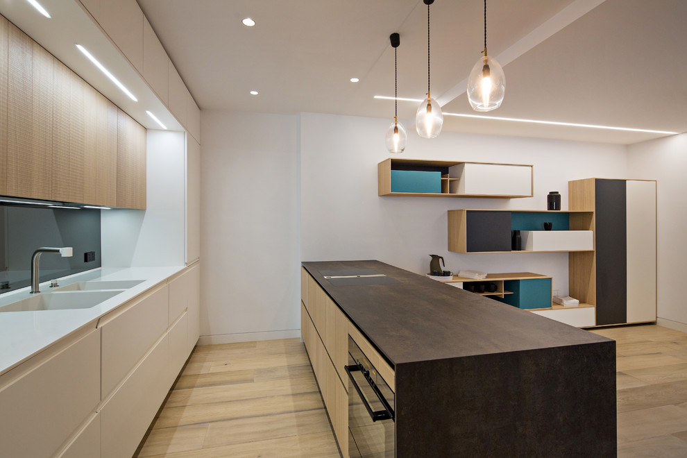 Inspiration for a small contemporary galley open plan kitchen in Sydney with an integrated sink, flat-panel cabinets, white cabinets, black splashback, mirror splashback, stainless steel appliances, light hardwood floors, with island and multi-coloured floor.