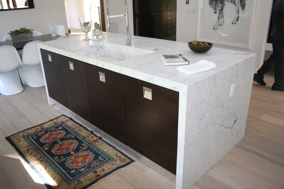 Modern eat-in kitchen in Los Angeles with marble benchtops, an integrated sink and flat-panel cabinets.